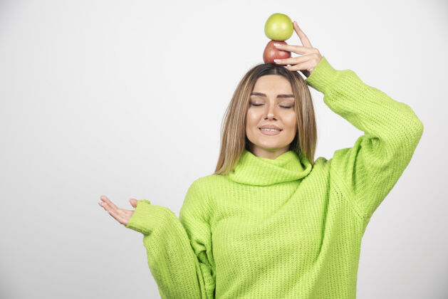 饮食身穿绿色t恤的年轻女子头顶举着两个苹果水果用餐绿色苹果