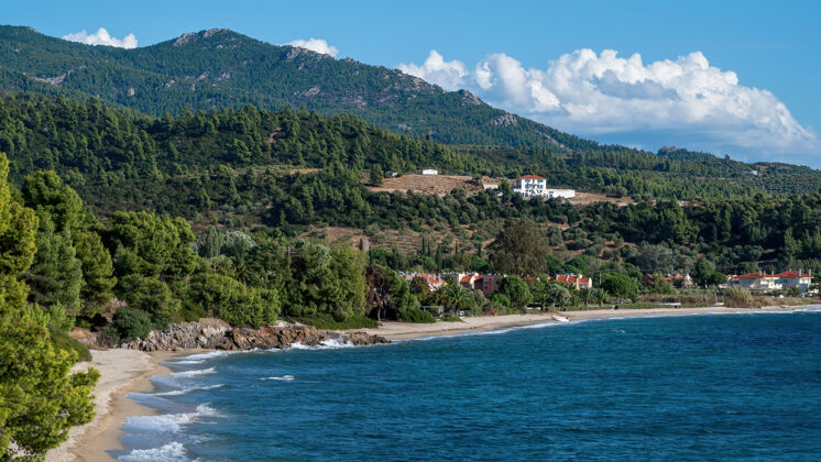 蓝色希腊爱琴海海岸 多岩石的小山上长着树木和灌木 建筑物位于海岸附近希腊语山水