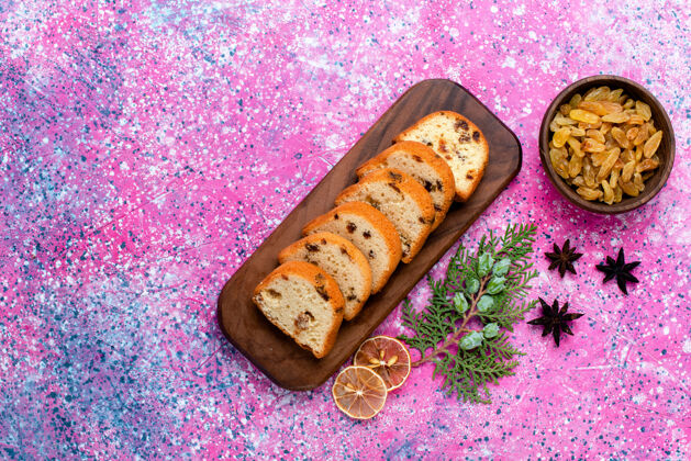 切俯瞰美味的葡萄干蛋糕 粉色桌子上的切片馅饼 烤馅饼 甜甜的饼干 饼干的颜色生的葡萄干盒子