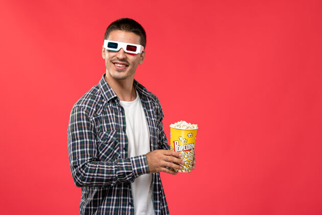 男人前视图年轻男子手持爆米花在d太阳镜上的红墙电影院电影电影院男性剧院