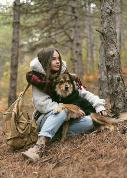 季节性年轻的女人和她的狗在森林里共度时光假期愉快放松