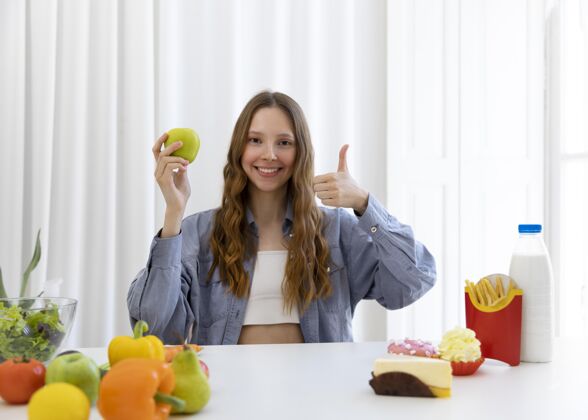食品拿着苹果和拇指的中枪女人健康营养模特