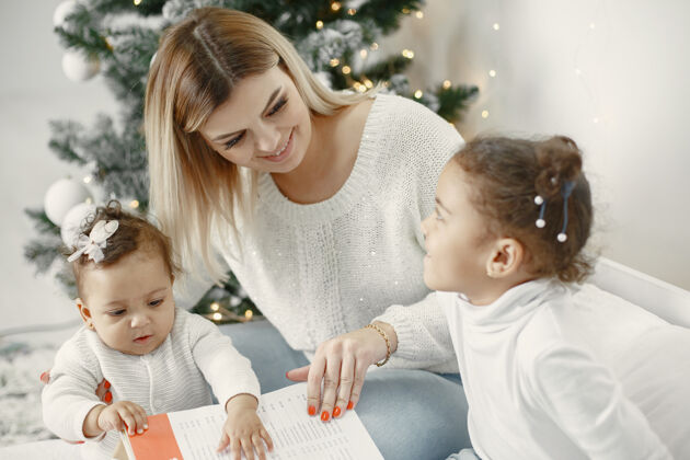 装饰人们在为圣诞节做准备母亲在和女儿们玩耍一家人在节日的房间里休息孩子穿着毛衣女人混合母亲