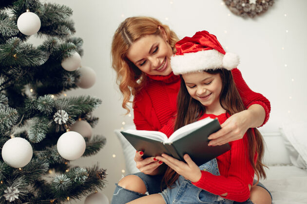 杉木人们在为圣诞节做准备母亲在和女儿玩耍一家人在节日的房间里休息孩子穿着红色毛衣圣诞老人小给予