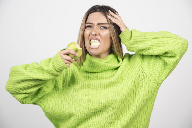 肖像穿着绿色t恤的年轻女子正在吃苹果水果吃营养