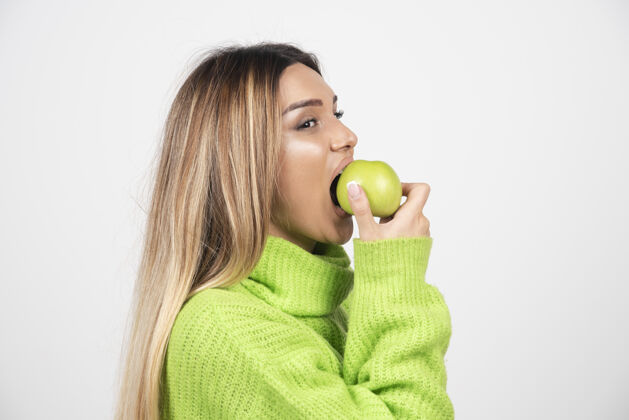绿色穿着绿色t恤的年轻女子正在吃苹果人水果吃