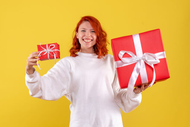 风车黄色墙壁上年轻女子拿着圣诞礼物的正面图礼物圣诞节年轻的女人