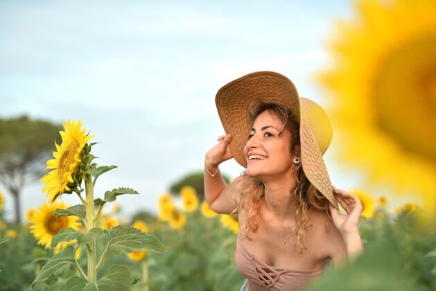 自然在向日葵地里戴着帽子微笑的年轻女子欢乐田野花园