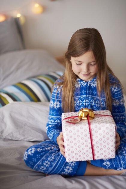 孩子床上放着圣诞礼物的小女孩微笑睡衣圣诞老人
