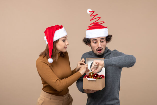 心情喜庆的心情与兴奋酷夫妇戴着红色圣诞老人帽灰色镜头圣诞节成人镜头