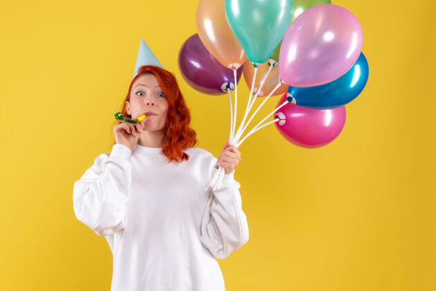 礼物黄色墙壁上手持彩色气球的年轻女子的正视图女性生日气球