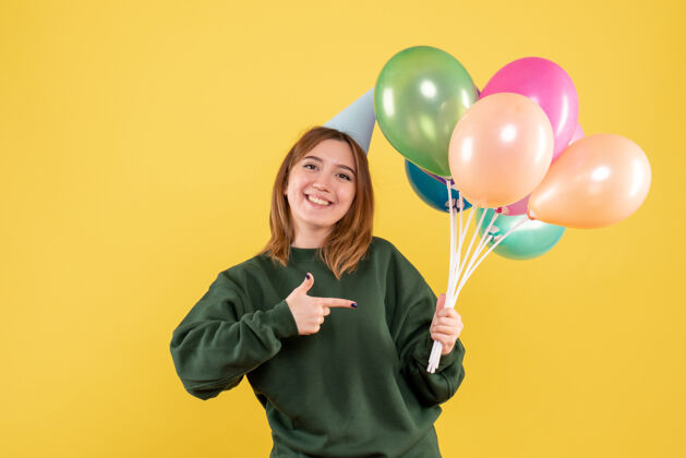 吹正面图：带着彩色气球的年轻女性圣诞节乐趣颜色