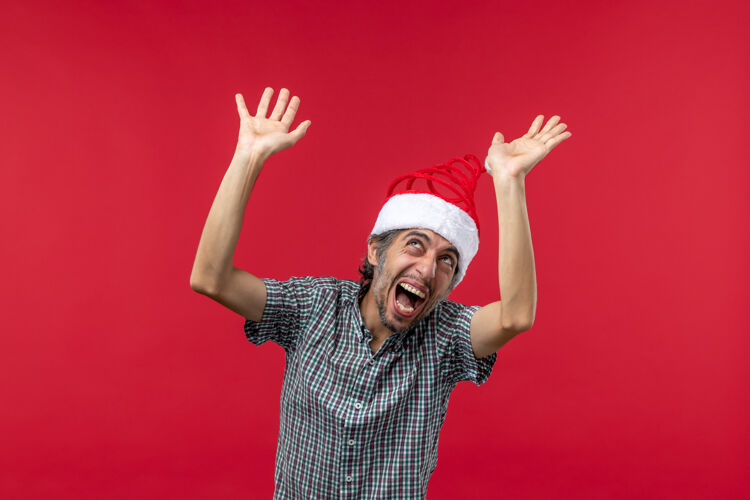 男人红墙上一脸惊恐的年轻人的正面图表情脸圣诞节