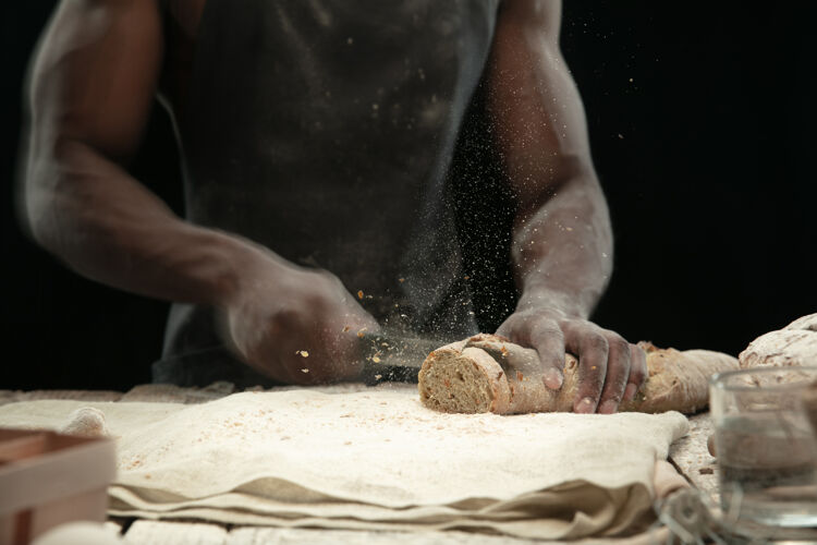 男性非洲裔美国人用菜刀切新鲜面包的特写镜头手可爱人