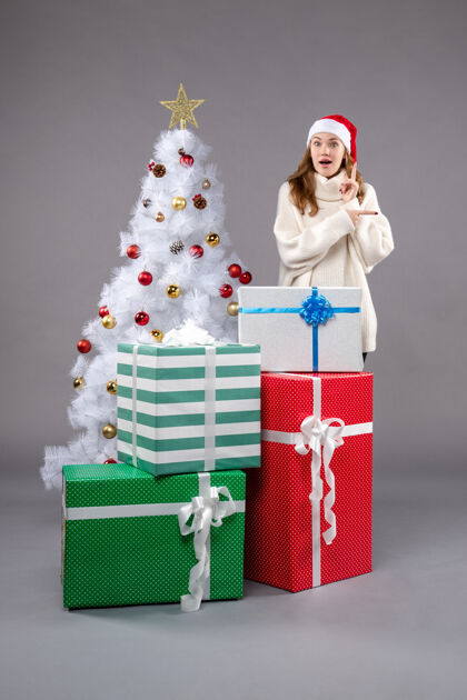 圣诞老人年轻女性在灰色地板上圣诞礼物新年圣诞假期购物周围帽子
