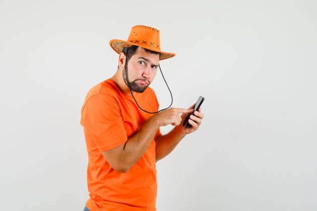 衬衫年轻人用手机穿着橙色t恤 戴着帽子 神情沉思时尚帽子模特