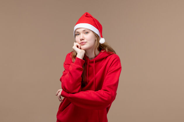 人物前视图圣诞女孩与棕色背景模型假日圣诞节红色斗篷摆姿势可爱圣诞女孩帽子