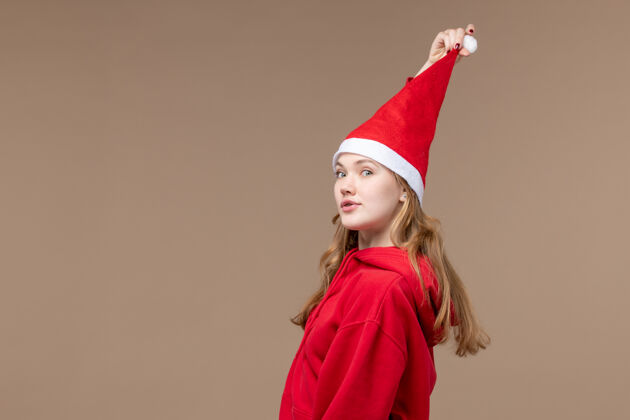 人正面图：圣诞假期 棕色背景上穿着红色斗篷的年轻女性年轻女性摩托板圣诞节