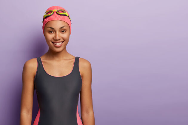 运动员健康的女游泳运动员戴着粉红色的帽子 护目镜 游泳服装 准备在游泳池锻炼非洲休息比赛