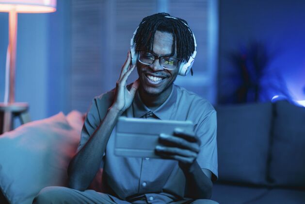 现代在家使用平板电脑和耳机的快乐男人人年轻人科技