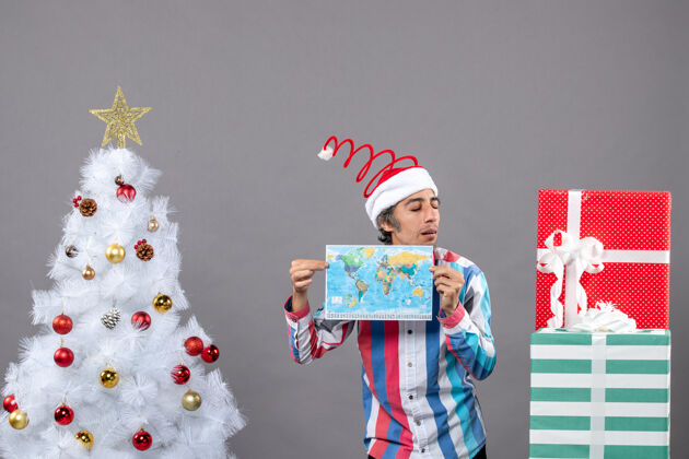 快乐正面图：戴螺旋弹簧圣诞帽的男人双手拿着地图举行圣诞螺旋