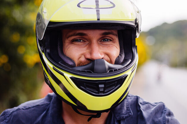 滑板车在泰国繁忙的公路边骑摩托车的戴着黄色头盔的男摩托车手的画像人自然自行车