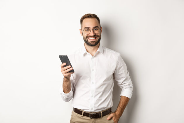 成人帅哥经理用智能手机微笑着高兴 发短信 站着正式通信智能手机