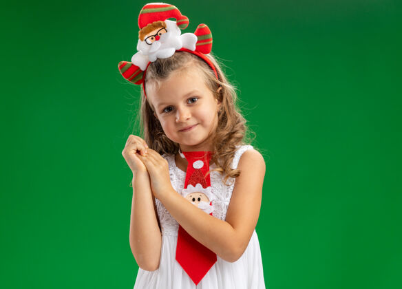 抱着高兴的小女孩戴着圣诞发箍打着领带 手牵着手孤立地放在绿色的背景上女孩头发手