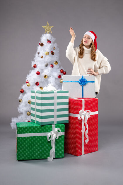 礼物年轻的女性在灰色的礼物女性圣诞树圣诞树