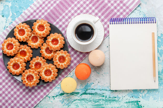 顶部俯瞰美味的小饼干与法国马卡龙和咖啡蓝桌饼干饼干甜甜的糖的颜色咖啡饼干生的