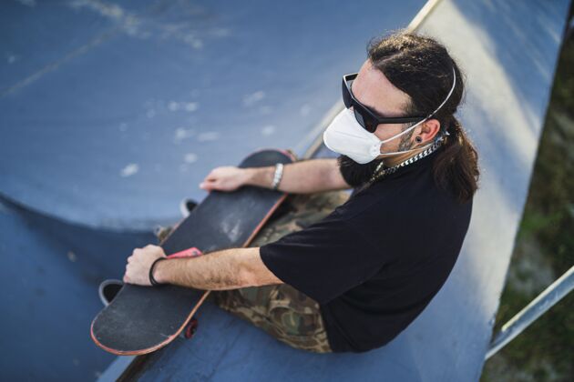 设备一个胡须男戴着面罩坐在混凝土表面的顶视图黑色材料举行