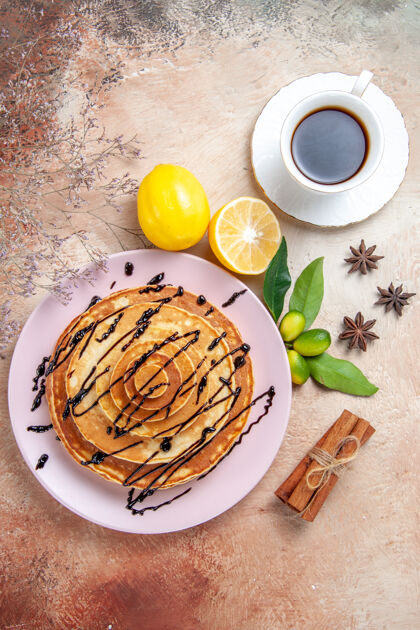 盘子五颜六色的桌子上装饰着巧克力糖浆和柠檬茶的简易煎饼的垂直视图美味营养品柠檬
