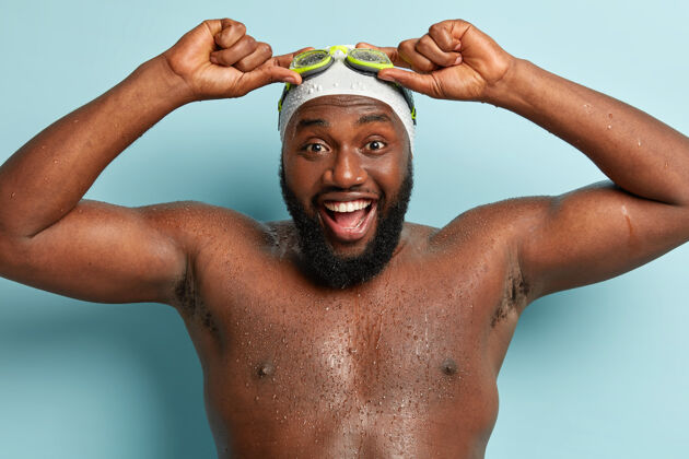 情绪长胡子的快乐男人裸体的特写镜头 潜水课后有正面印象 手拿护目镜 肌肉发达 皮肤黝黑 站在室内游泳 爱好 休息的概念不刮胡子体操室内