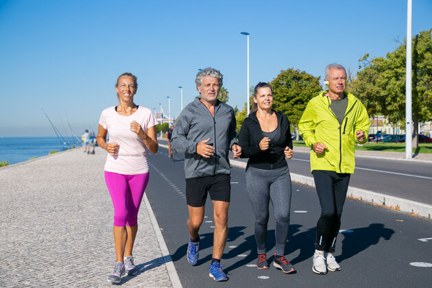 社区一群穿着运动服的成熟人士 沿着河岸慢跑全程拍摄退休或积极的生活方式理念运动装慢跑活动