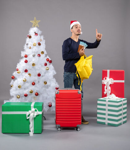 背包一个戴着圣诞帽 带着红色手提箱的年轻人正在检查他的黄色背包检查周围年轻