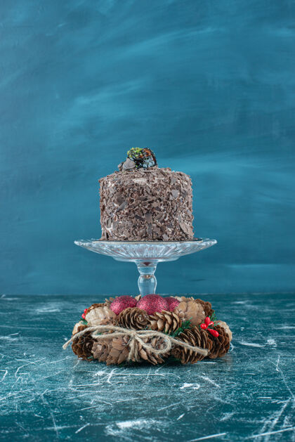 蛋糕底座上的巧克力蛋糕和蓝色的松果花环蛋卷可口松子