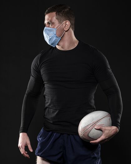 男子带着医用面罩和球的男橄榄球运动员完全垂直球员