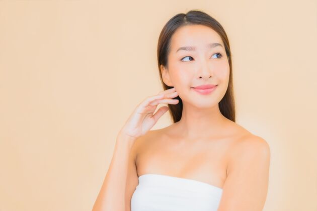 护理肖像美丽的年轻亚洲女子在温泉与自然化妆米色美国人皮肤护理脸