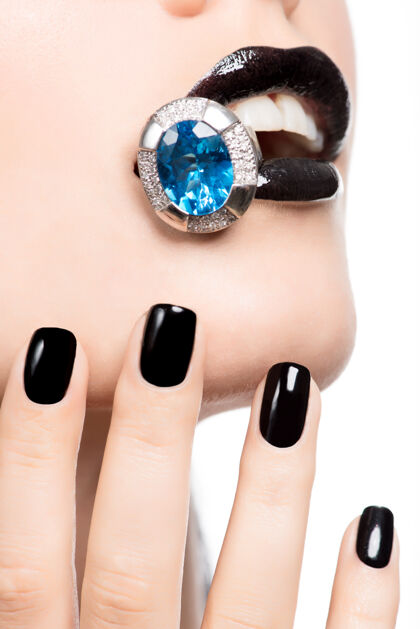 闪亮一个女人的嘴唇和指甲被涂成亮黑色的宏观照片Bijouterie珠宝指甲