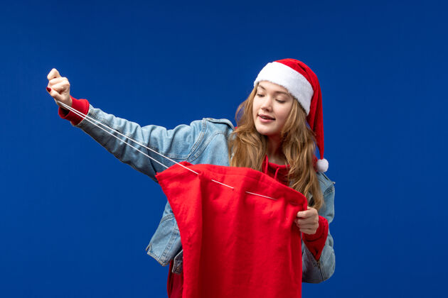 蓝色前视图年轻女性拿着一个蓝色背景的圣诞假期礼物袋背景快乐前面