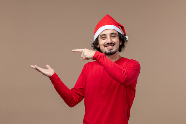 人物正面图棕色背景上带着微笑的年轻男性情感节日圣诞节帽子快乐年轻男性