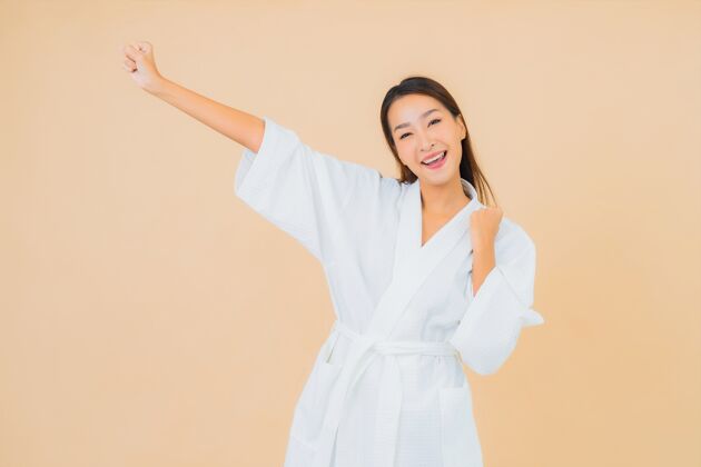肖像肖像美丽的亚洲年轻女子穿着米色的微笑浴袍清洁女士面部