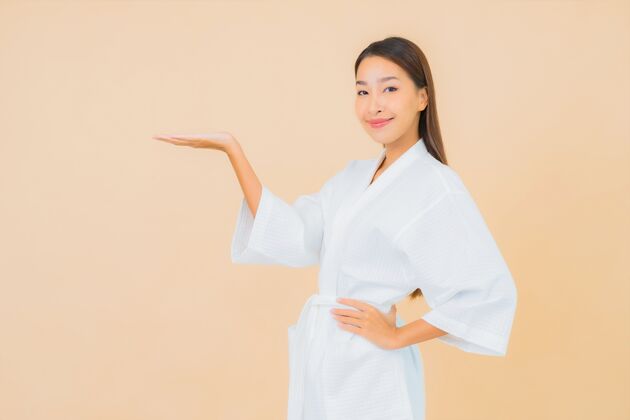 面部肖像美丽的亚洲年轻女子穿着米色的微笑浴袍治疗诊所面部