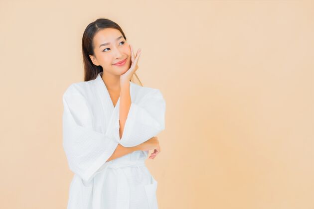 护肤肖像美丽的亚洲年轻女子穿着米色的微笑浴袍成人女士保湿