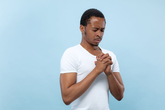 手势身穿白衬衫的非洲裔美国年轻人的特写肖像闭上眼睛祈祷 看起来充满希望手祈祷看起来