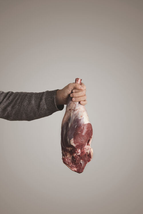 肉男人的手在灰色毛衣举行冰岛生肉羊腿肉 灰白色背景隔离古饮食 有机食品牛排手最小