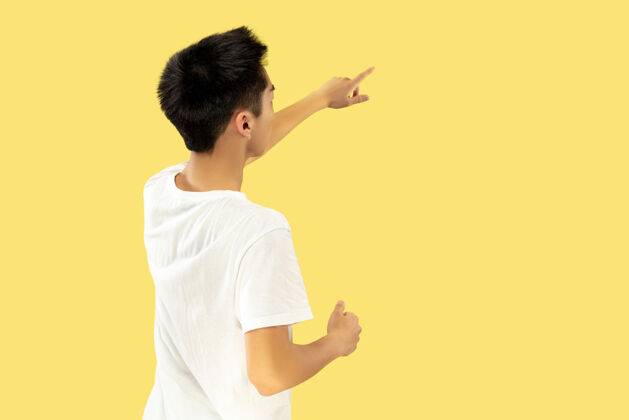 人韩国年轻人的肖像穿白衬衫的男模指向广告的地方人类情感的概念 面部表情流行的颜色人快乐男人
