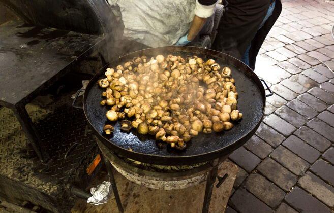 封闭新鲜蘑菇在户外的大金属锅里煎配料口感季节