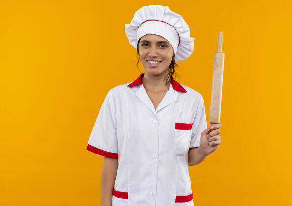 穿着面带微笑的年轻女厨师穿着厨师制服拿着擀面杖与复印空间女拿着制服