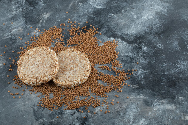 早餐两个脆面包和生荞麦放在大理石表面面包圆形大米